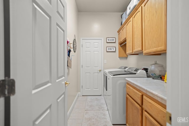 clothes washing area featuring cabinets, washing machine and dryer, and light tile patterned floors