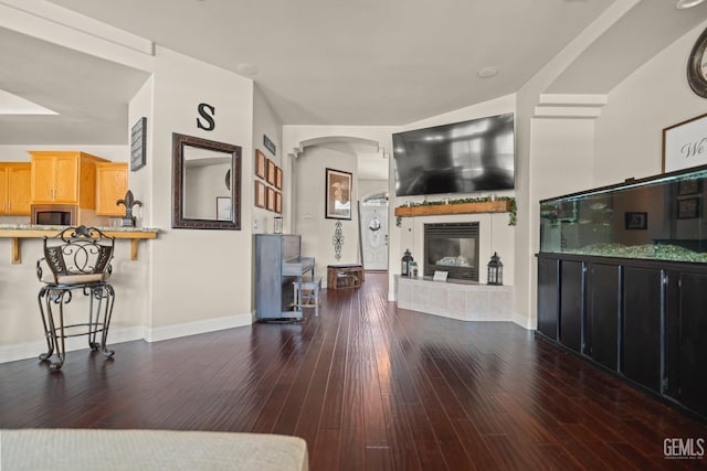 living room featuring dark wood-type flooring and a tiled fireplace