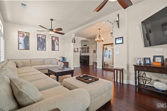 living room with dark hardwood / wood-style flooring and ceiling fan with notable chandelier