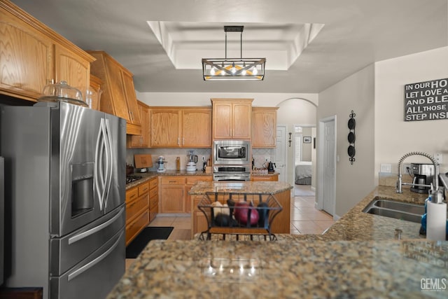 kitchen featuring sink, tasteful backsplash, stone countertops, appliances with stainless steel finishes, and a tray ceiling