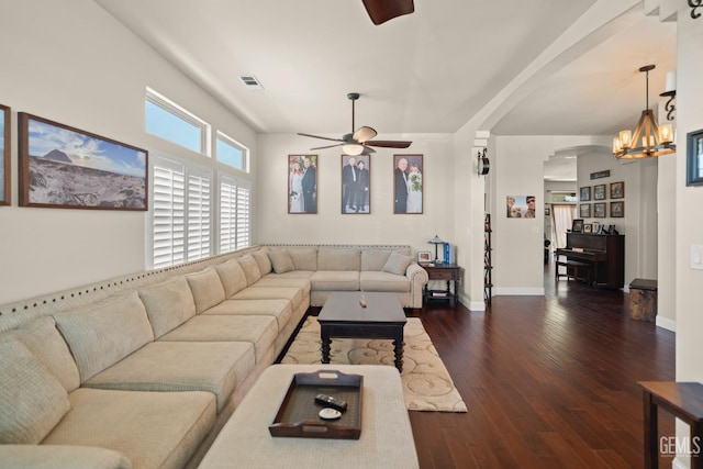 living room featuring dark wood-type flooring and ceiling fan with notable chandelier