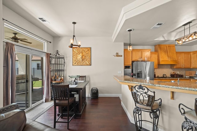 kitchen featuring decorative light fixtures, a breakfast bar, custom range hood, and stainless steel fridge with ice dispenser