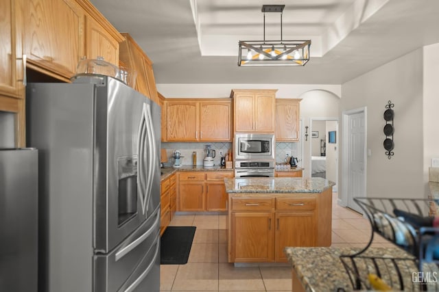 kitchen featuring a kitchen island, backsplash, light tile patterned floors, light stone counters, and stainless steel appliances