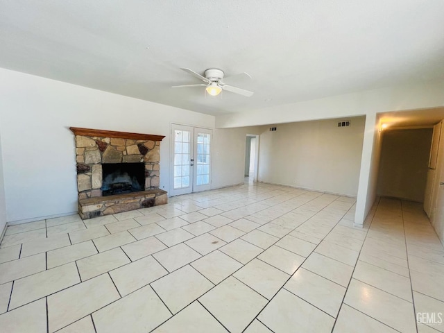 unfurnished living room with visible vents, a ceiling fan, french doors, a fireplace, and light tile patterned flooring