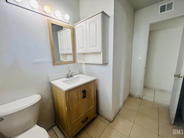 bathroom featuring visible vents, baseboards, toilet, tile patterned flooring, and vanity