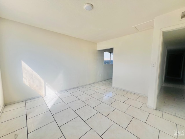 spare room with attic access, light tile patterned flooring, and visible vents