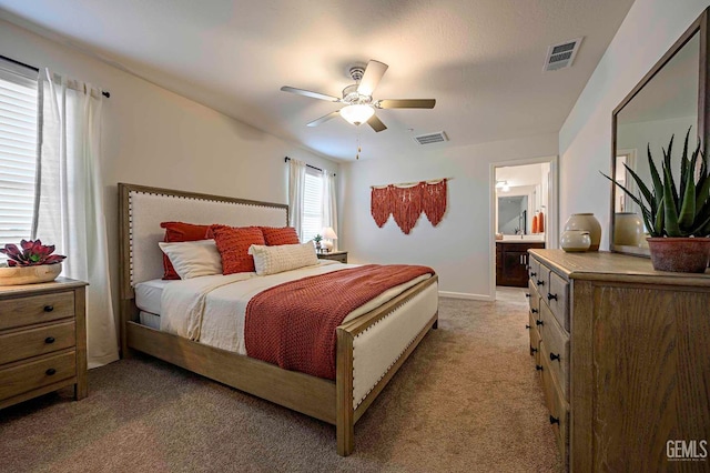 carpeted bedroom with ensuite bath and ceiling fan