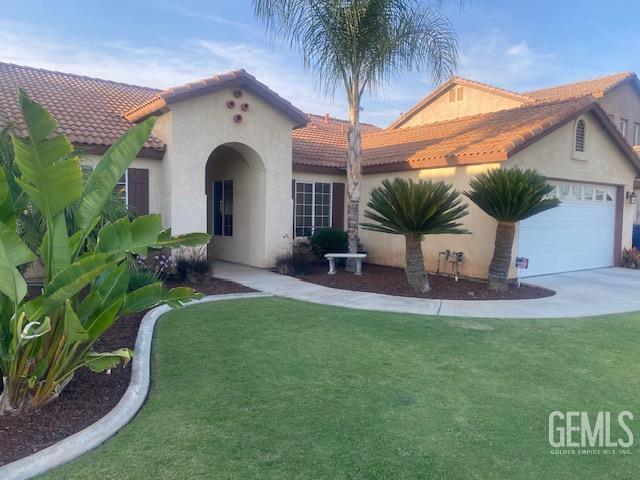 11422 Pacific Harbor Ave, Bakersfield, CA 93312 - mediterranean / spanish home with an attached garage, a tiled roof, stucco siding, and a front yard
