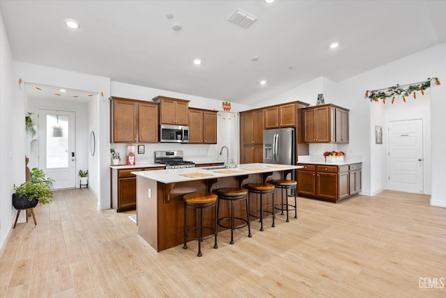 kitchen featuring a center island with sink, light countertops, visible vents, appliances with stainless steel finishes, and light wood-style floors