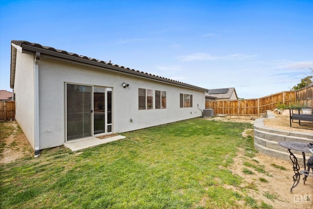 rear view of property featuring central AC, a yard, a fenced backyard, and stucco siding