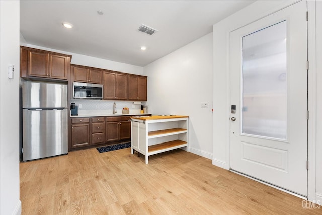 kitchen with tasteful backsplash, visible vents, appliances with stainless steel finishes, light wood-style floors, and a sink