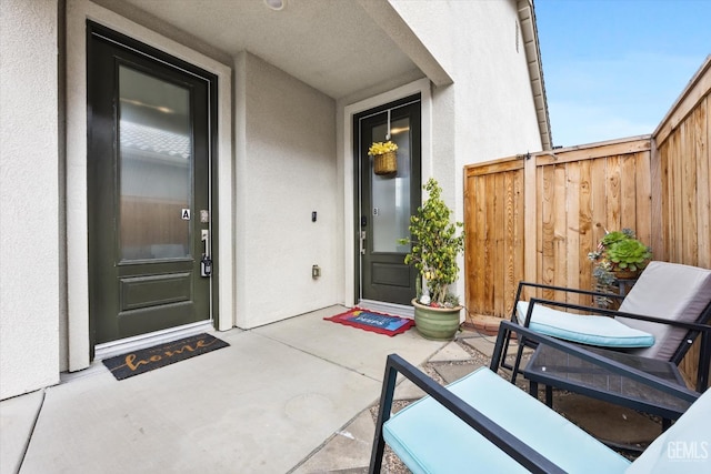 property entrance featuring fence and stucco siding