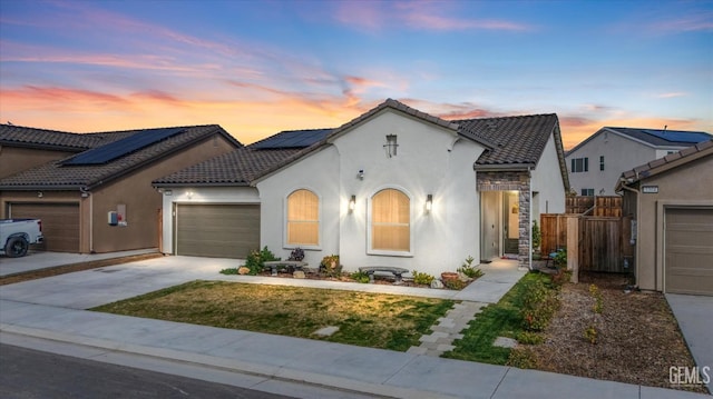 view of front of house featuring a tile roof, stucco siding, concrete driveway, fence, and a garage