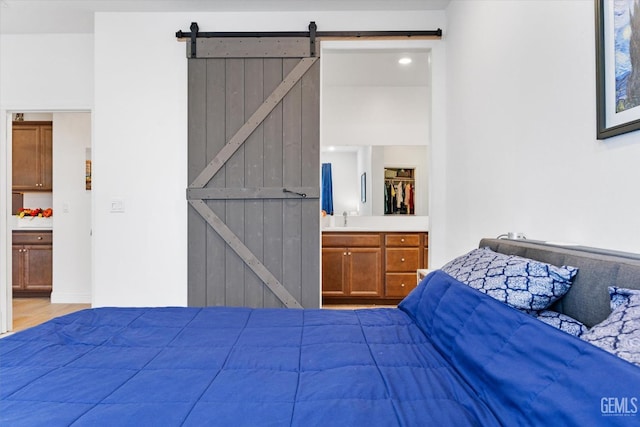 bedroom with connected bathroom, a sink, and a barn door