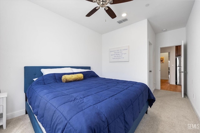 carpeted bedroom with a ceiling fan, freestanding refrigerator, visible vents, and baseboards