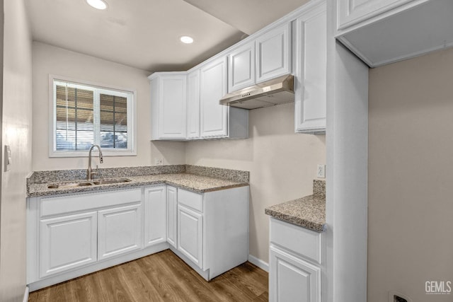 kitchen with white cabinetry, sink, and light hardwood / wood-style flooring