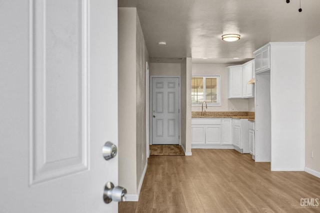 kitchen with sink, white cabinets, and light hardwood / wood-style flooring