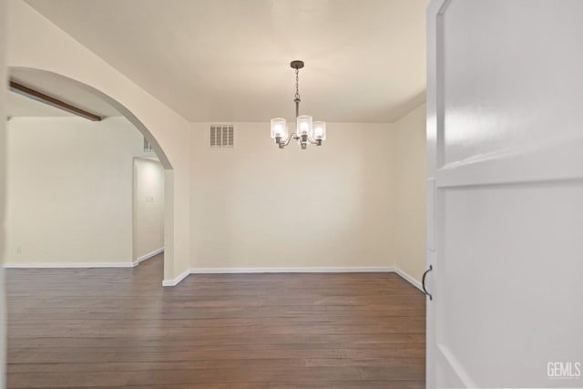 empty room with a chandelier and dark hardwood / wood-style flooring