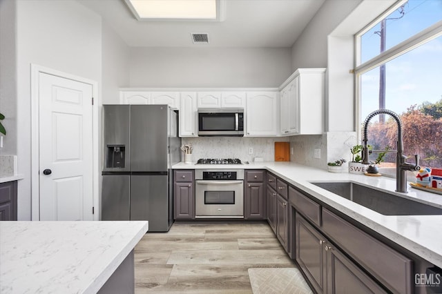 10809 Mirage Dr, Bakersfield, CA 93311 - kitchen featuring appliances with stainless steel finishes, white cabinets, light wood-style floors, and tasteful backsplash