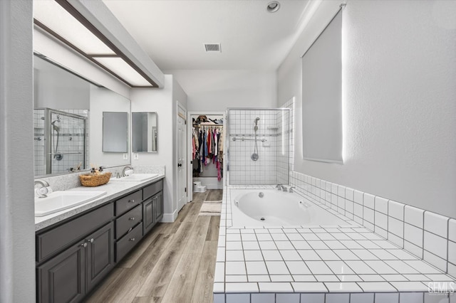10809 Mirage Dr, Bakersfield, CA 93311 - full bathroom featuring a shower stall, double vanity, a bath, a walk in closet, and wood finished floors
