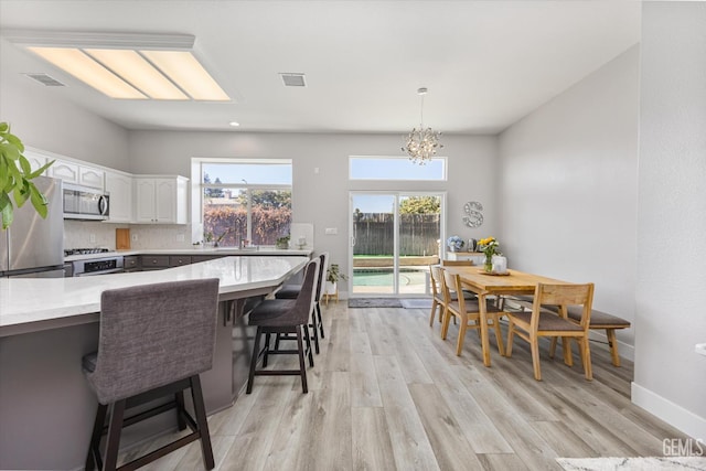 10809 Mirage Dr, Bakersfield, CA 93311 - kitchen with appliances with stainless steel finishes, a chandelier, a kitchen bar, light wood finished floors, and recessed lighting