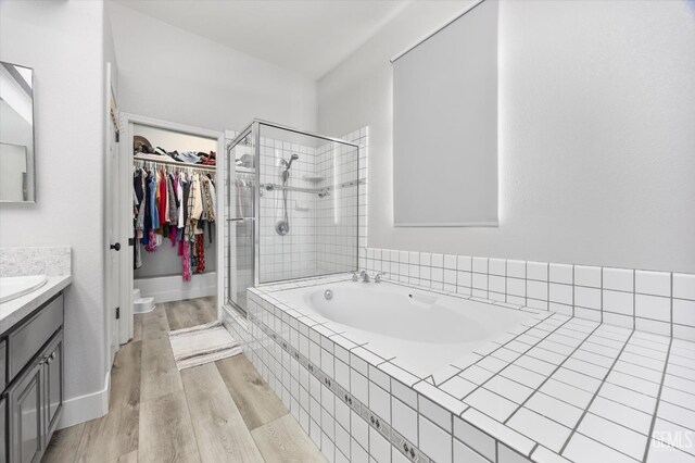 10809 Mirage Dr, Bakersfield, CA 93311 - bathroom with vanity, a stall shower, a bath, a walk in closet, and wood finished floors