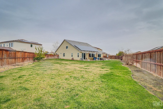 rear view of house with a lawn and solar panels