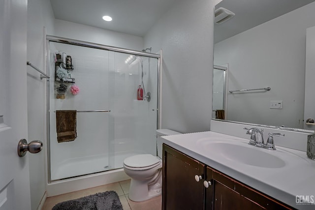 bathroom with tile patterned floors, toilet, a shower with shower door, and vanity