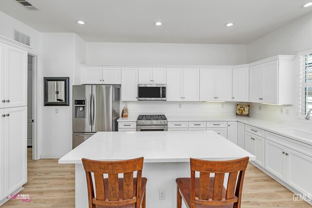 5903 Gold Ranch Way, Bakersfield, CA 93306 - kitchen featuring stainless steel appliances, a kitchen island, white cabinetry, light wood finished floors, and a kitchen breakfast bar