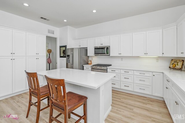 5903 Gold Ranch Way, Bakersfield, CA 93306 - kitchen with stainless steel appliances, a kitchen bar, white cabinets, light wood-style flooring, and recessed lighting