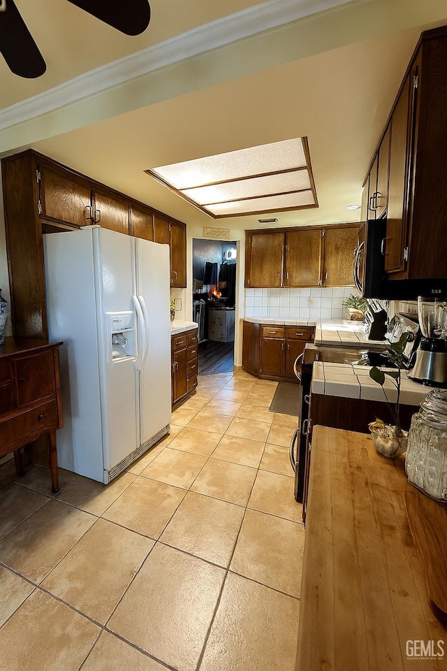 9125 Gleeson Ct, Bakersfield, CA 93311 - kitchen with white fridge with ice dispenser, tile counters, ornamental molding, light tile patterned flooring, and dark brown cabinetry