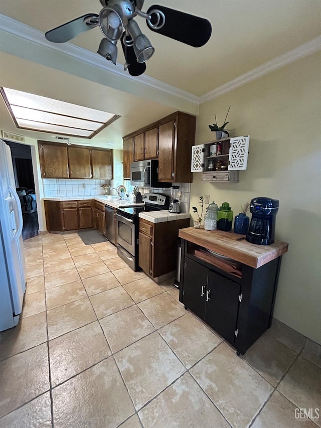9125 Gleeson Ct, Bakersfield, CA 93311 - kitchen featuring appliances with stainless steel finishes, crown molding, light tile patterned floors, light countertops, and ceiling fan