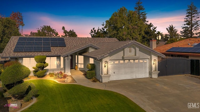 view of front of home featuring a lawn, solar panels, and a garage