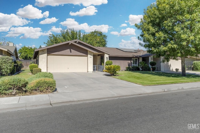 ranch-style house featuring a garage, a front yard, and solar panels