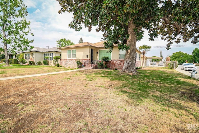 ranch-style house with stucco siding, a front yard, and brick siding