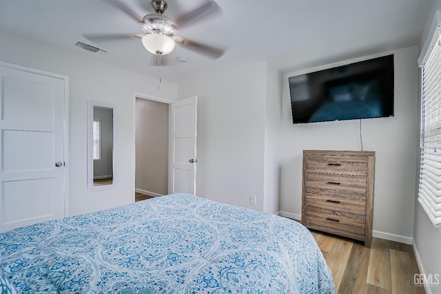 bedroom with light wood finished floors, a ceiling fan, visible vents, and baseboards