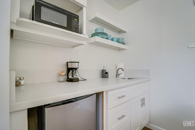 bar featuring baseboards, black microwave, and a sink