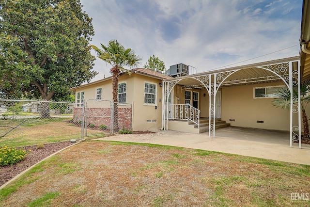 back of house with central air condition unit, fence, crawl space, a gate, and stucco siding