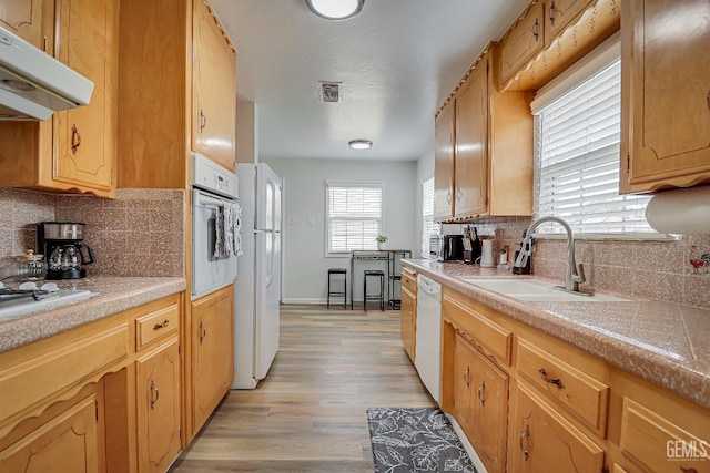 kitchen featuring visible vents, light countertops, a sink, white appliances, and under cabinet range hood