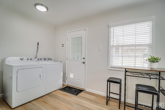 washroom featuring laundry area, washing machine and dryer, baseboards, and wood finished floors