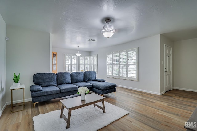 living area with light wood-style floors, baseboards, and visible vents