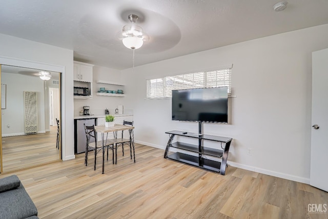 dining space featuring light wood-type flooring, baseboards, and a ceiling fan