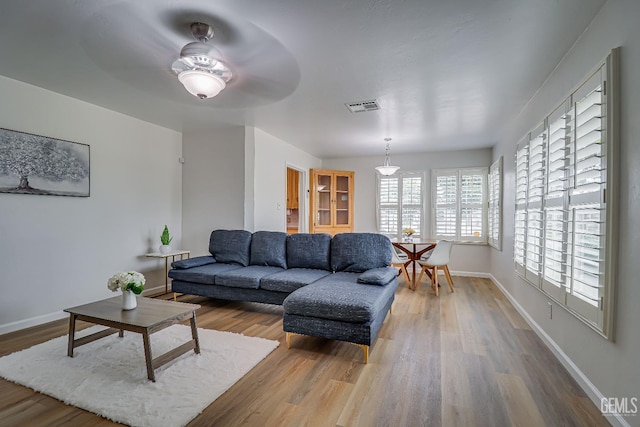 living area with wood finished floors, visible vents, and baseboards