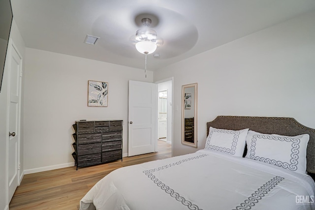 bedroom featuring a ceiling fan, wood finished floors, visible vents, and baseboards