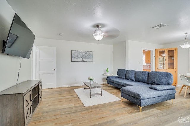 living area featuring visible vents, a ceiling fan, light wood-style flooring, and baseboards