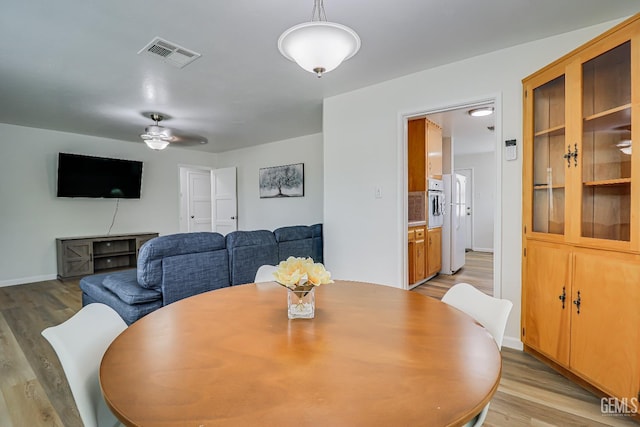 dining room featuring ceiling fan, baseboards, visible vents, and light wood-style floors