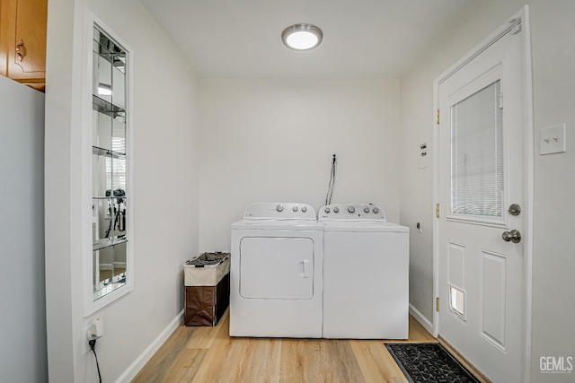 washroom featuring cabinet space, baseboards, light wood finished floors, and independent washer and dryer