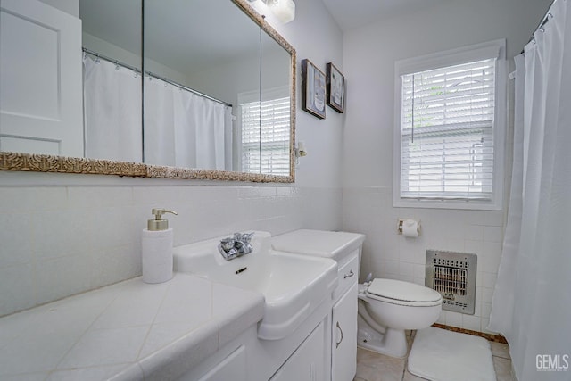 full bath with tile walls, heating unit, toilet, vanity, and tile patterned flooring