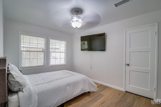 bedroom with a ceiling fan, visible vents, light wood-style flooring, and baseboards