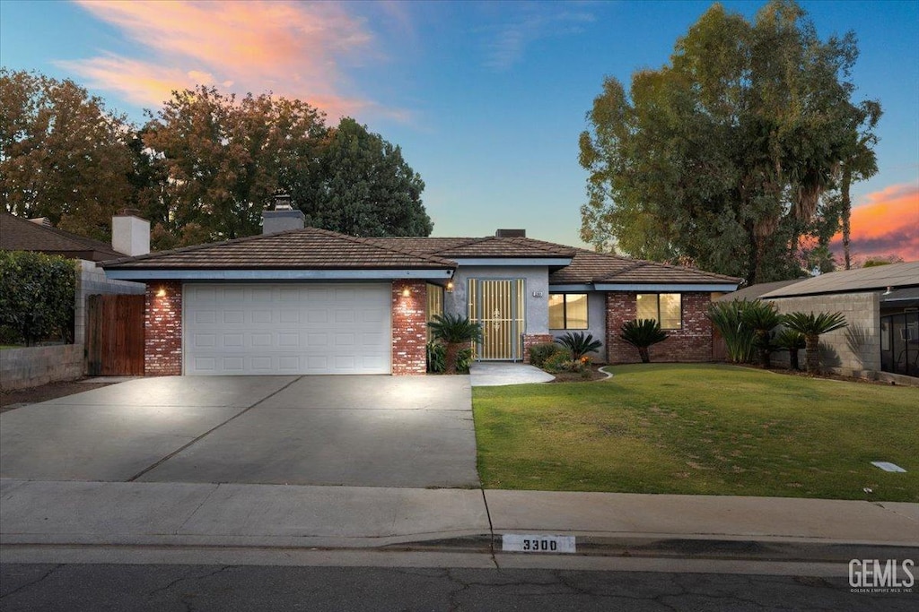 ranch-style home with a garage and a yard